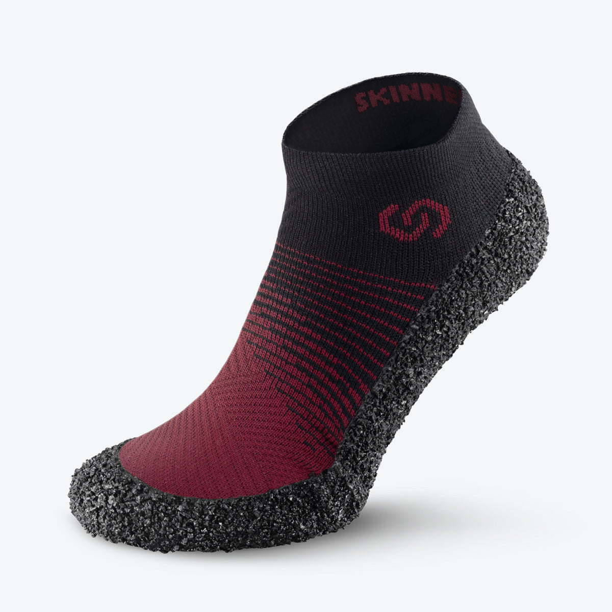 Skinners sock shoe with red and black fabric upper and textured rubber sole.